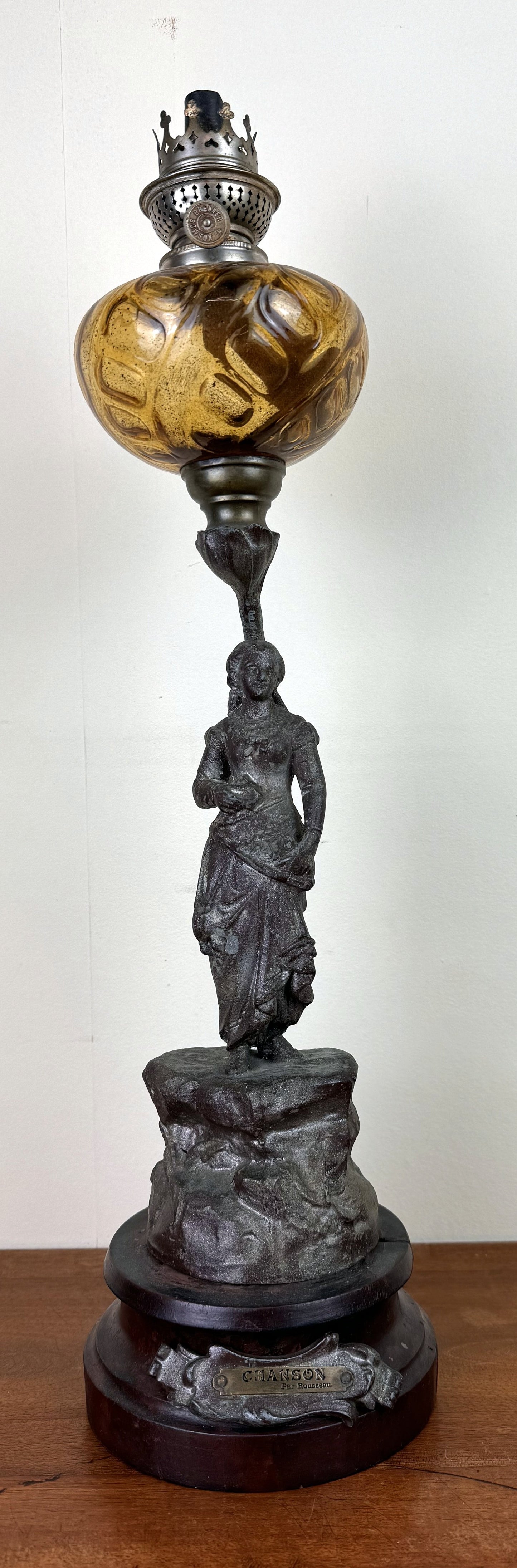Grande lampe a pétrole montée sur une statue en régule intitulée "Chanson par Rousseau"
