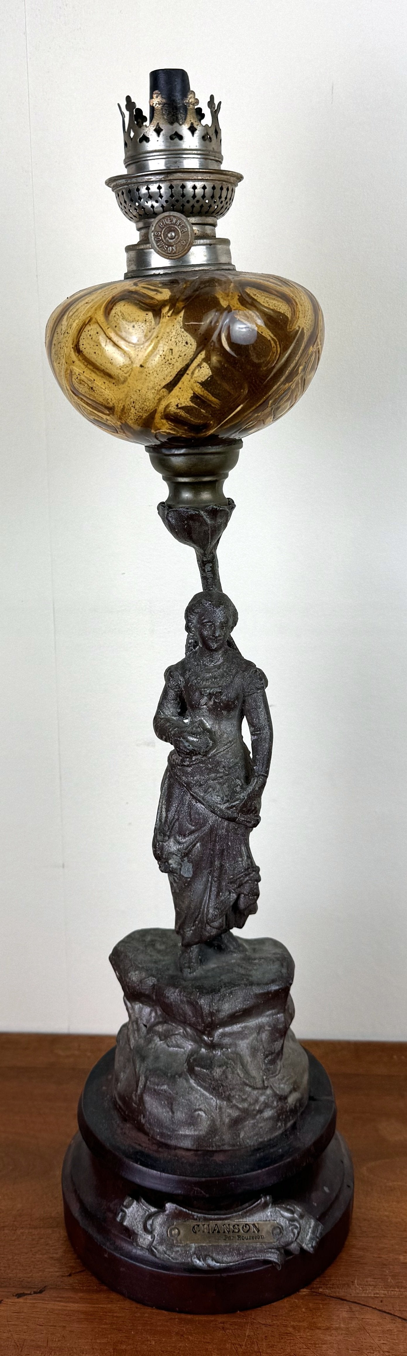 Grande lampe a pétrole montée sur une statue en régule intitulée "Chanson par Rousseau"